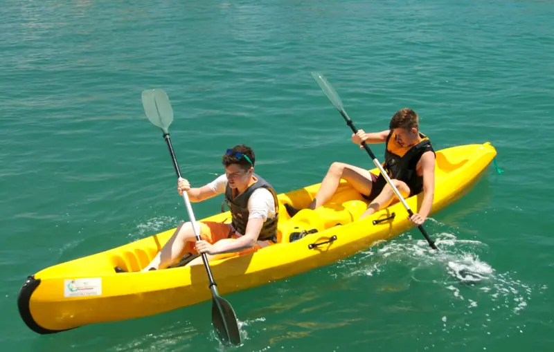 Two people paddle a yellow double kayak